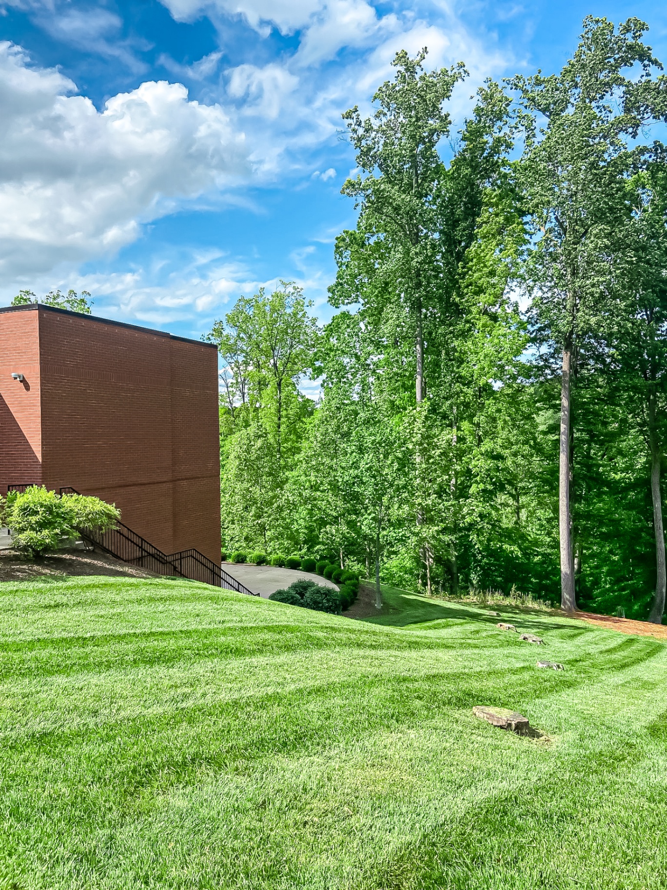 Professional striped lawn mowing on hillside at commercial brick office building in Tennessee by Prestige Landscape