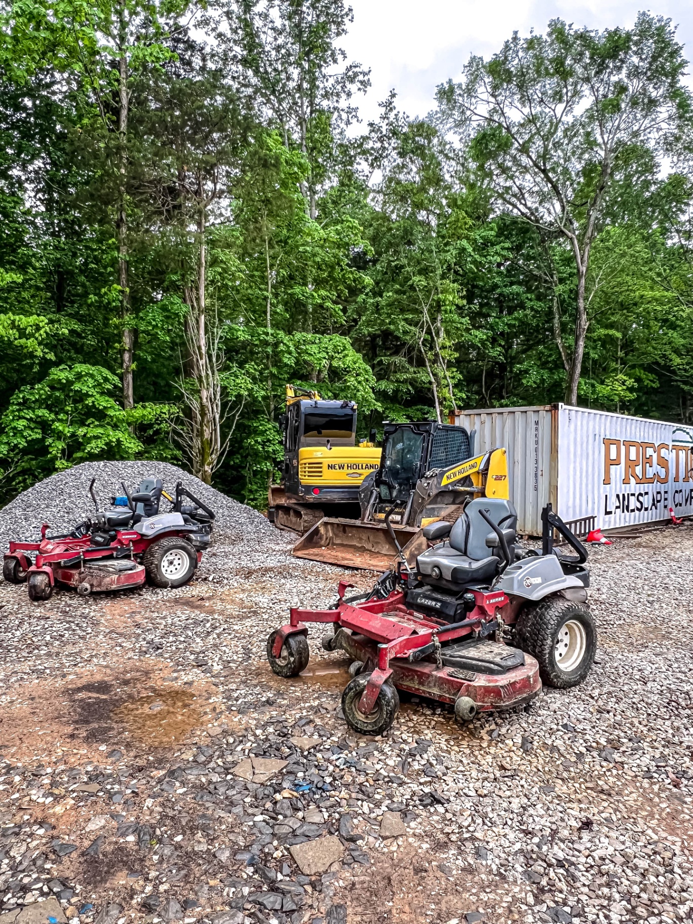 Commercial lawn mowers and excavation equipment at Prestige Landscape Company yard in Tennessee