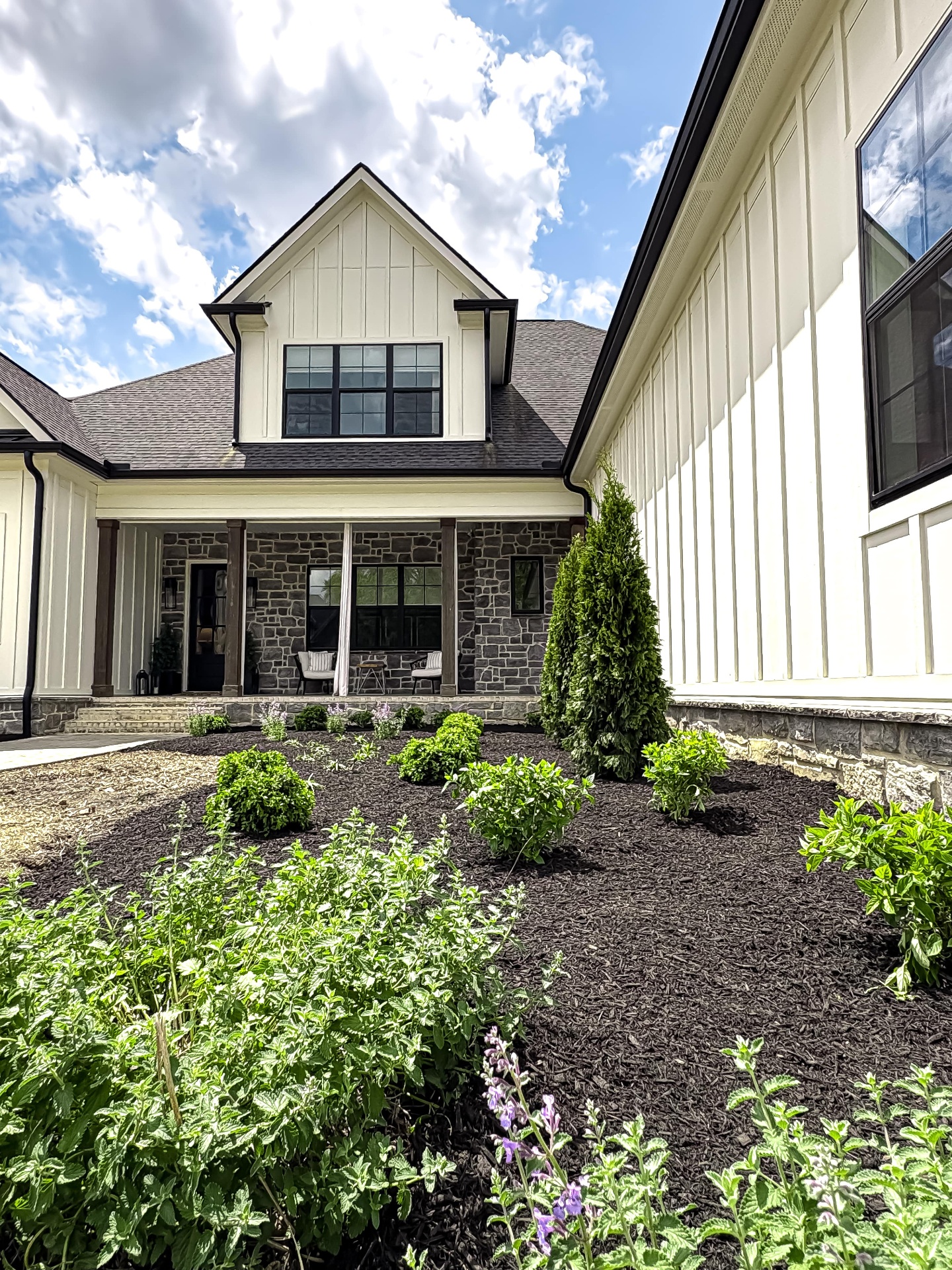 Professional mulch installation and shrub planting at luxury Tennessee home with stone exterior